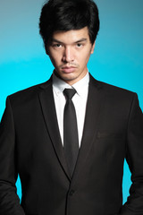 Asian man in black suit and white shirt on blue background