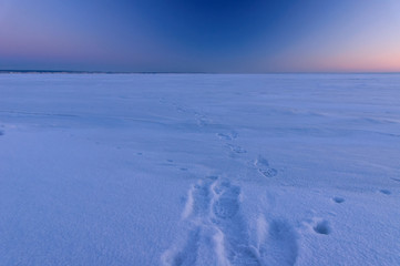 Footprints in snow at cold winter evening. Frozen river Volga