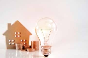 Light bulb and pile of coins. Saving money for buying a house, H