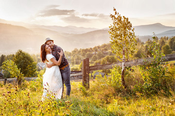 loving couple in the mountains near a wooden fence.