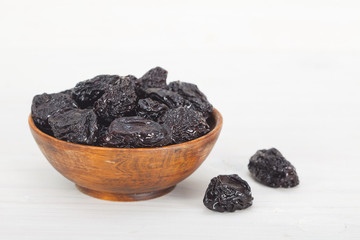 Dry plums or prunes in wooden bowl