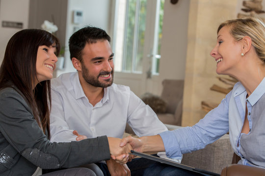 young Hispanic couple shaking hands with realtor