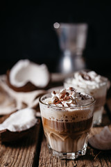 Coconut latte on a wooden table. Broken coconut. Low key food photo.