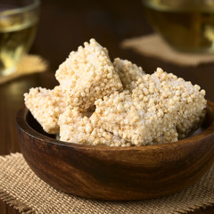 Baked marshmallow, popped quinoa and coconut bars in wooden bowl, photographed with natural light (Selective Focus, Focus on the front of the bar on the top)