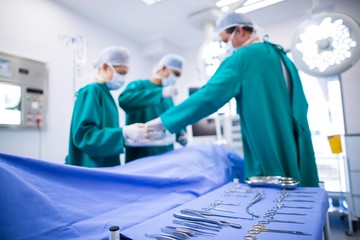 Surgeons performing operation in operation theater - obrazy, fototapety, plakaty