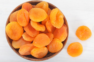 Healthy dried apricots in wooden bowl, top view