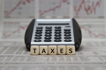 Taxes word with calculator on newspaper background