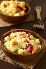 Salat aus Sauerkraut, Apfel, Kartoffeln und Speck in Holzschüssel, fotografiert mit natürlichem Licht (Selektiver Fokus, Fokus in die Mitte des ersten Salats)