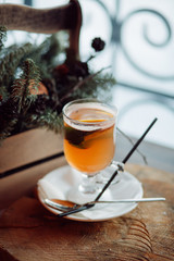 Glass of delicious orange glintwein or mulled hot wine thread on vintage wooden winter background