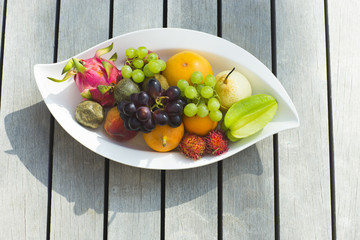 Tropical fruit on a white plate on a wooden surface.