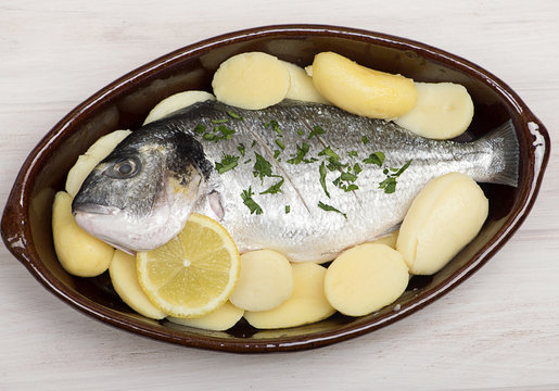 Raw fish with potatoes is about to be cooked. Horizontal outdoors shot