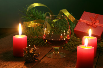 Brandy glass and candles on black background