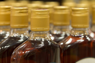 Top of plastic bottles with cognac or brandy standing in the liquor store. From the side.