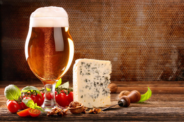 Glass of beer and blue cheese on brown vintage background