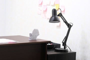 Interior of an office room with chair, table, lamp and stationery on it