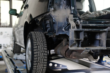 Black crashed car on stocks in a car repair station