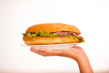 Woman eats hamburger isolated over white background