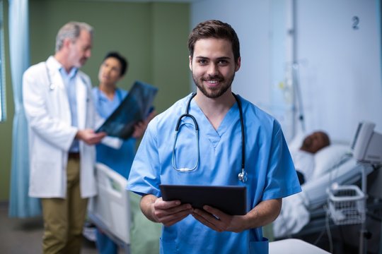 Portrait of male nurse using digital tablet in ward