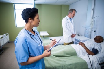 Obraz premium Female nurse writing on clipboard during visit 