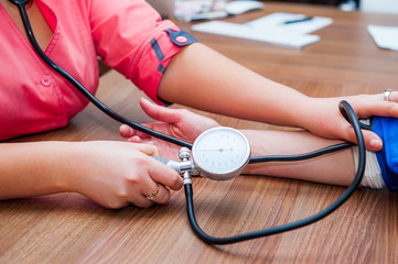 Close up view of female medicine doctor measuring blood pressure to her patient. Hands close up. Healthcare, healthy lifestyle and medical service concept