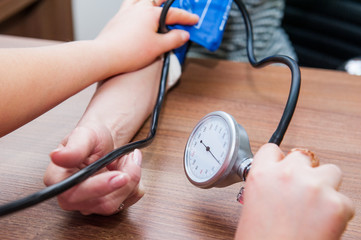 Close up view of female medicine doctor measuring blood pressure to her patient. Hands close up....
