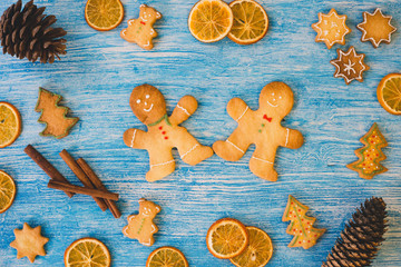 Christmas cookies, orange, cinnamon and pine cones on blue wooden background. Festive decorations