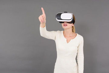 Junge Frau mit VR Brille auf grauem Hintergrund