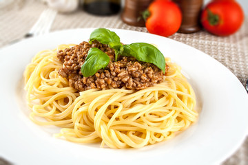 Spaghetti bolognese with basil on white plate