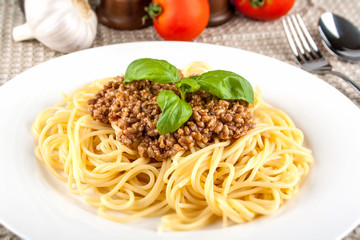 Spaghetti bolognese with basil on white plate