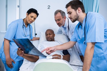 Obraz premium Doctor and nurse discussing x-ray with patient in ward