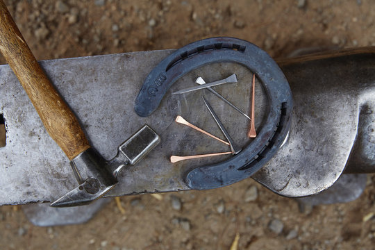 Overhead view of horseshoe with hammer and nails on anvil