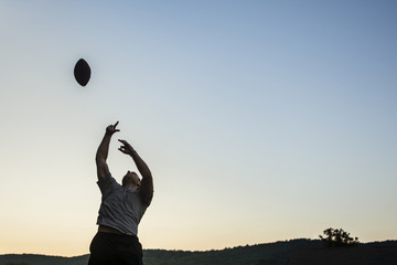 Low angle view of man playing rugby against clear sky during sunset