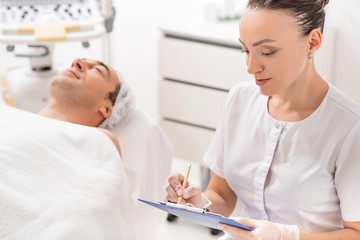 Obraz premium Professional cosmetologist making notes before procedure