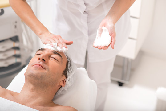 Senior male client getting facial skin treatment