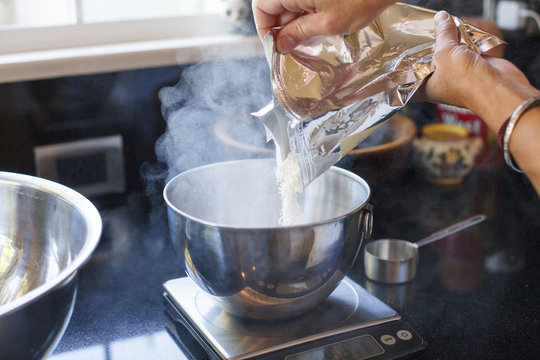 Cropped Image Of Woman Pouring Powder From Packet In Container On Weight Scale