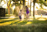 Cheerful siblings playing in sprinkler