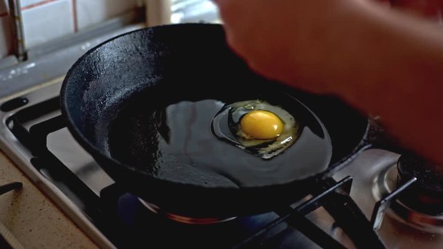 Two chicken eggs fried in a black frying pan on a gas stove.