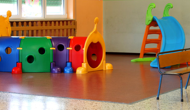 a tunnel shape game and a slide in the large hall of kindergarte