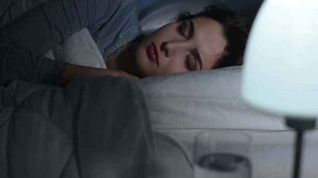Young woman sleeping in her bed at night under a soft duvet