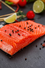 Fresh red fish (salmon fillet) and tomatoes, lime and chili pepper are ready for cooking.