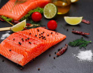 Fresh red fish (salmon fillet) and tomatoes, lime and chili pepper are ready for cooking.