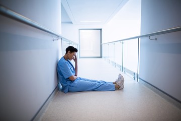 Tensed female nurse sitting in corridor