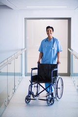 Portrait of female nurse standing with wheelchair 