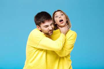 Fototapeta premium Young beautiful couple smohering each other over blue background.