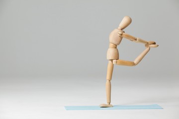 Wooden figurine exercising on exercise mat