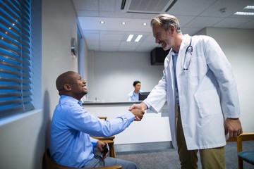 Male doctor shaking hands with patient - Powered by Adobe