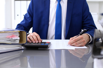 Close up view of bookkeeper or financial inspector hands making report, calculating or checking balance. Internal Revenue Service inspector checking financial document.