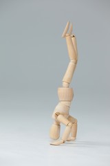 Wooden figurine performing a headstand