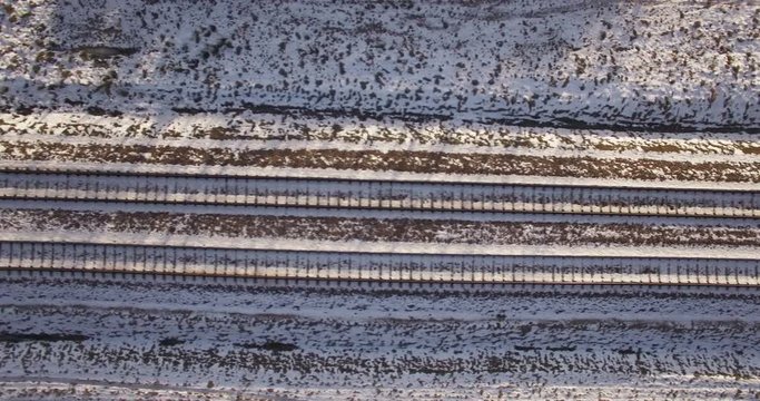 AERIAL. Camera flight above train tracks covered by snow. Overhead footage. 4k