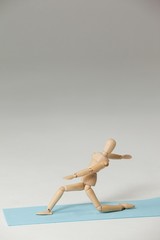 Wooden figurine exercising on exercise mat